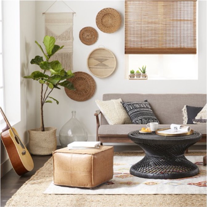 A natural bohemian living room with a leather pouf, modern loveseat, and woven round coffee table.