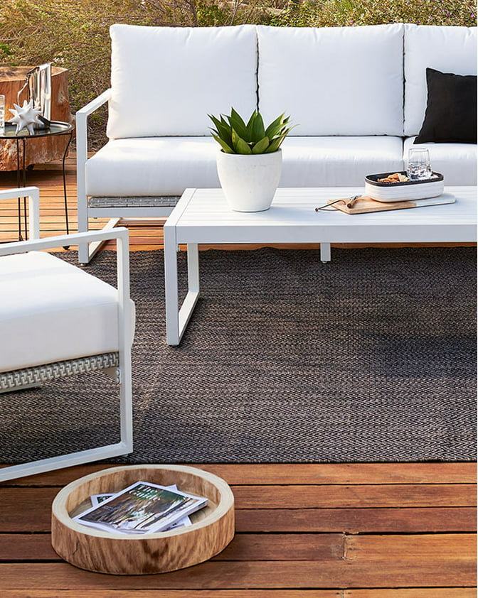 A modern white outdoor conversation set on a wooden patio. Links to patio furniture on dailysavesonline.com.